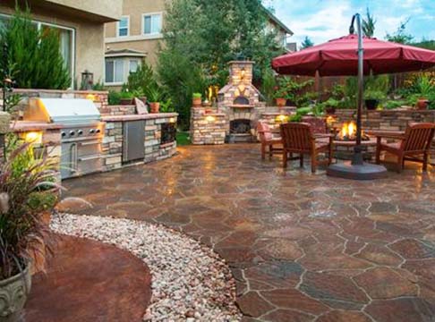 Beautiful outdoor living space with stone patio, fireplace, and lush landscaping